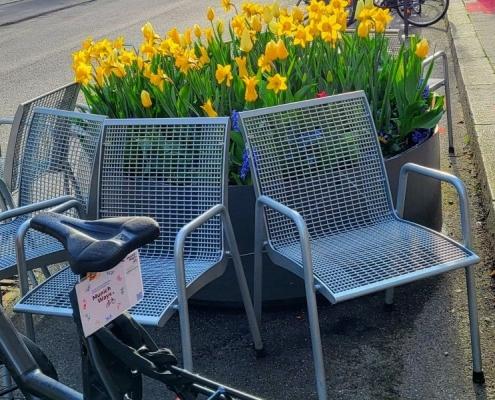 Sitzmöglichkeiten mit MunichWays Logo am Rad in der Weißenseestr.