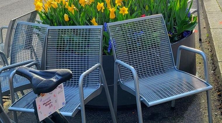 Sitzmöglichkeiten mit MunichWays Logo am Rad in der Weißenseestr.